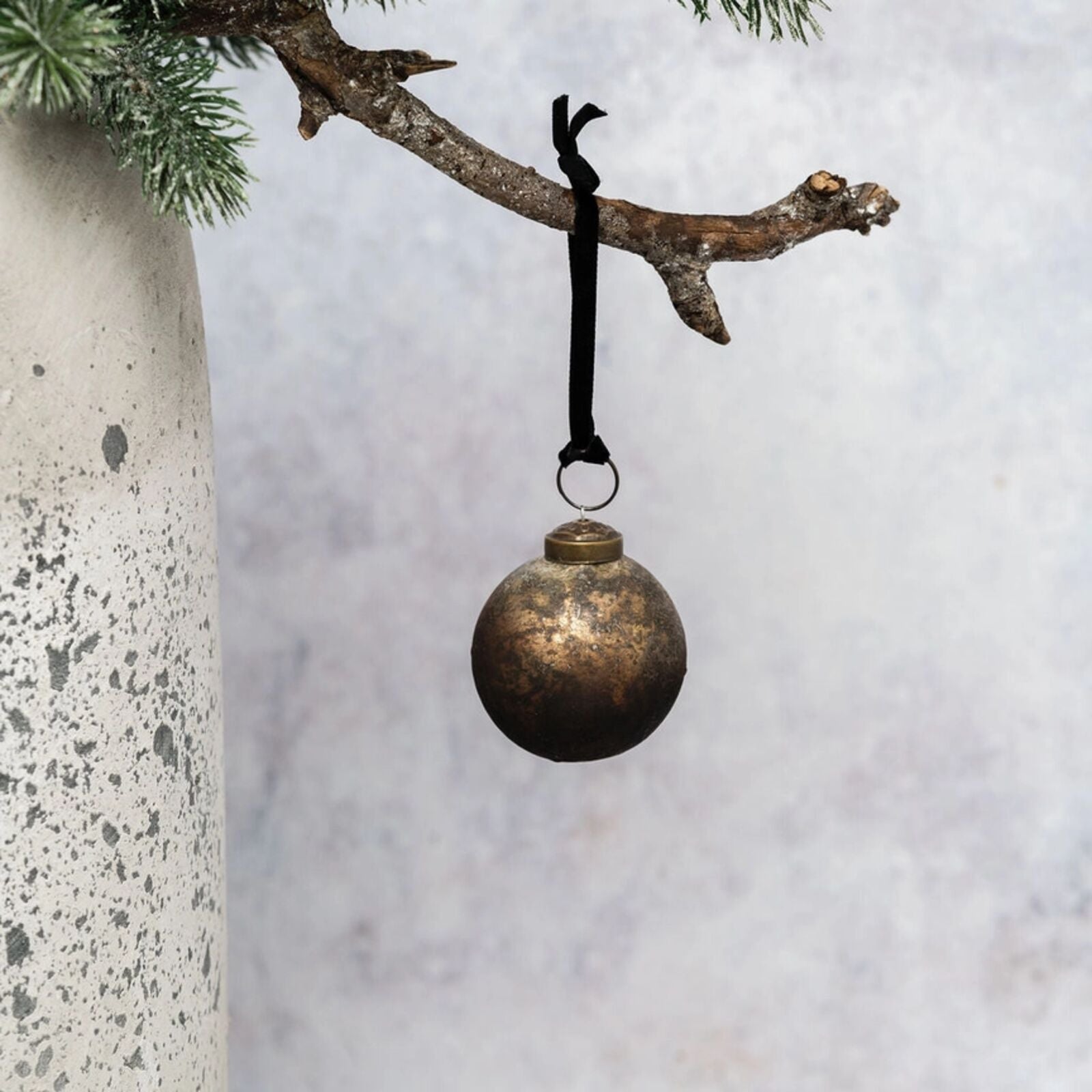 Bronze ornament hanging from a branch against a snowy background