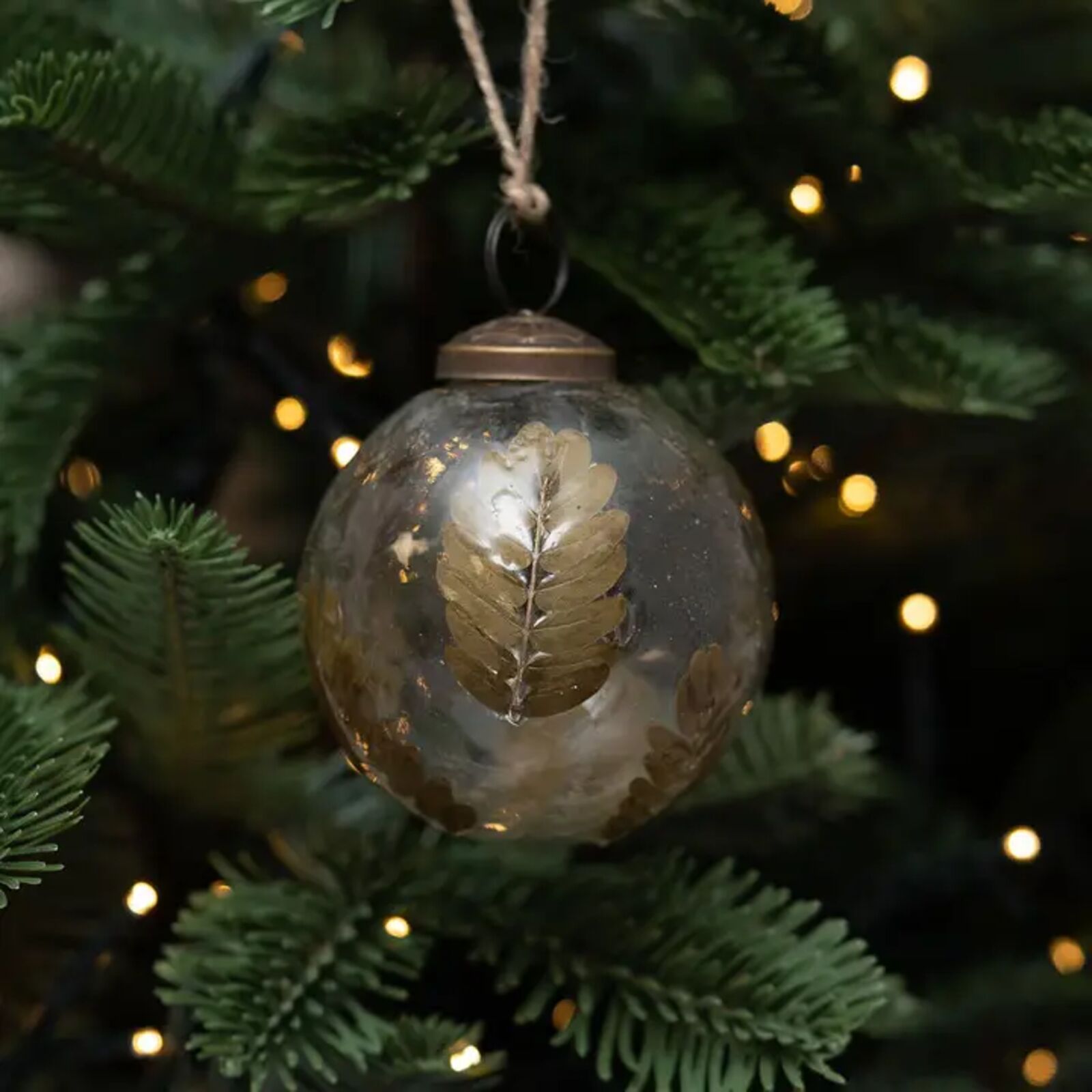 Decorative glass ornament with gold leaf on a Christmas tree with lights