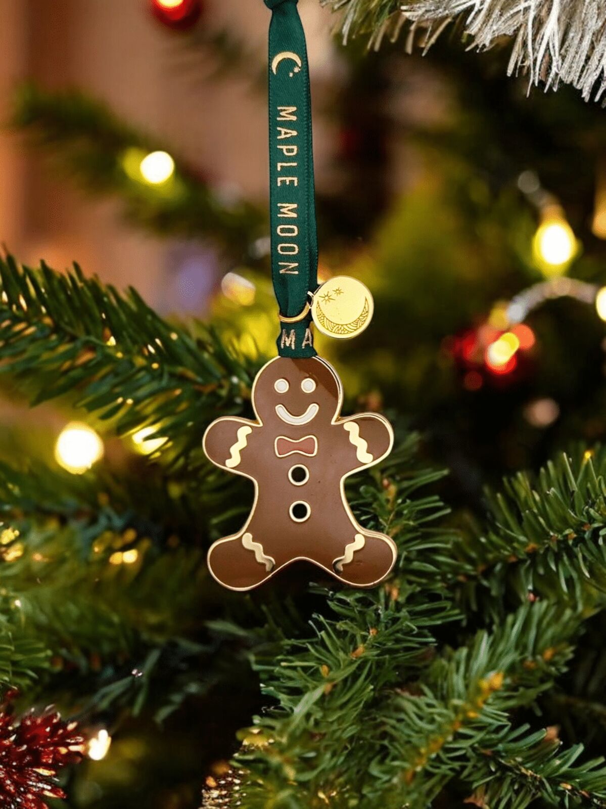 Gingerbread man ornament on a Christmas tree with 'Maple Moon' ribbon.