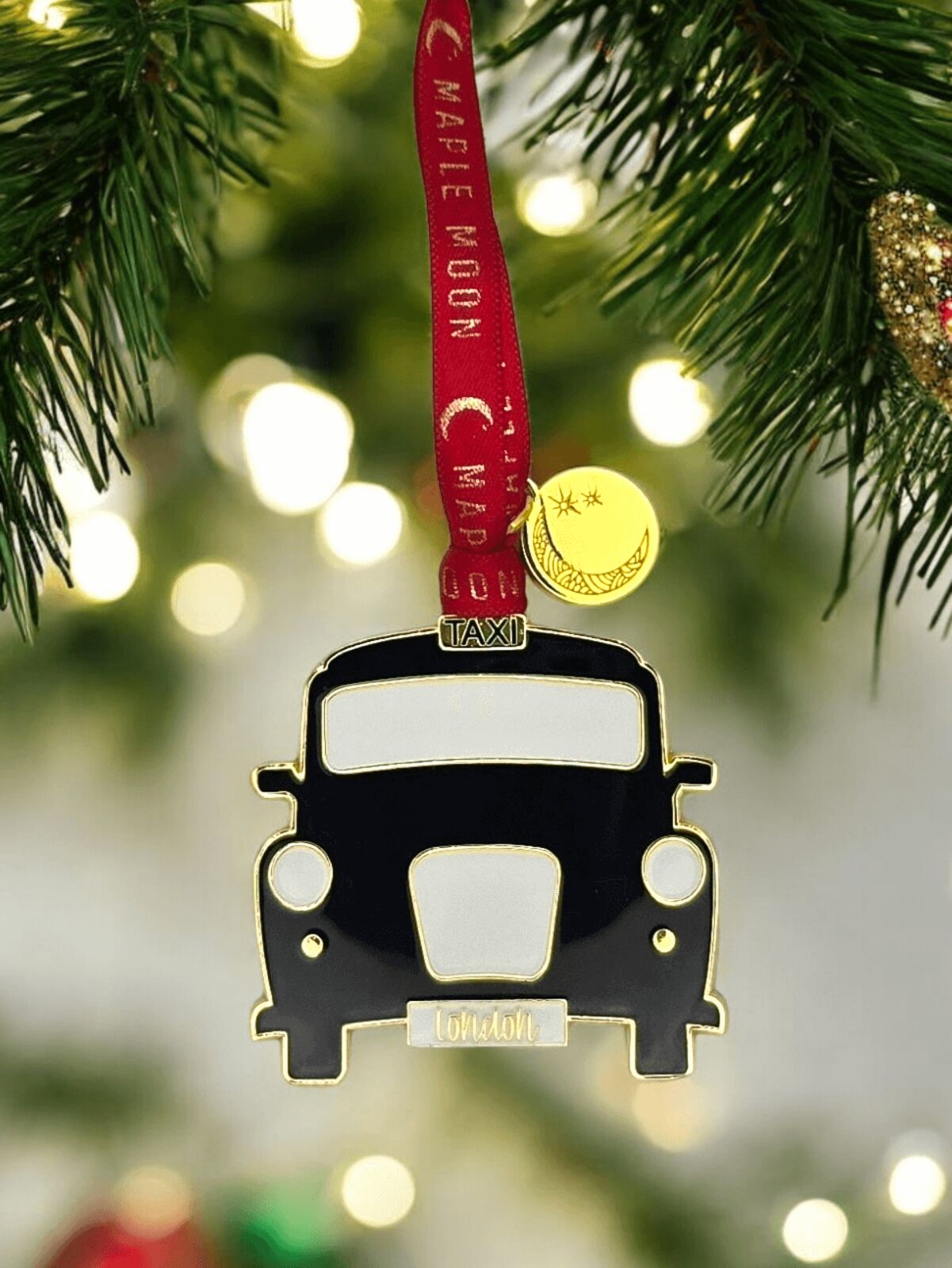 Taxi-shaped ornament on a Christmas tree with blurred lights in the background