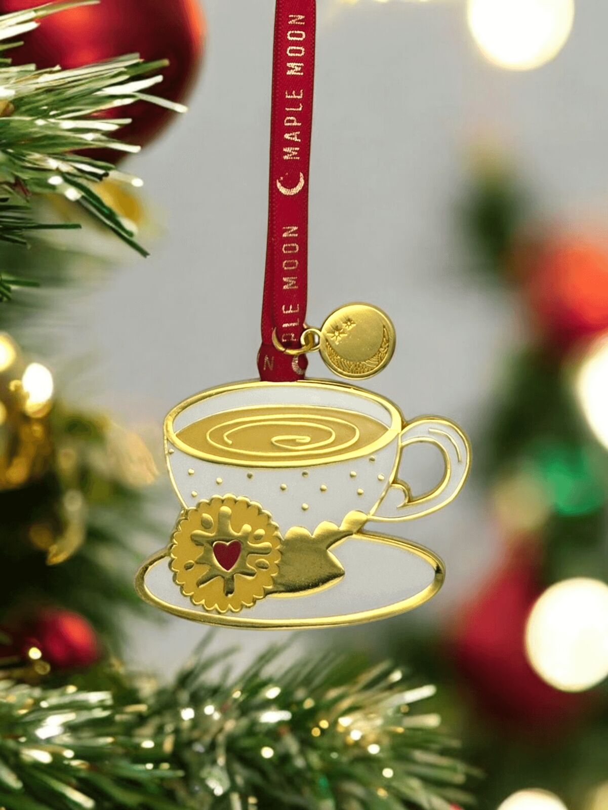 Gold Christmas ornament of a teacup with a cookie on a tree
