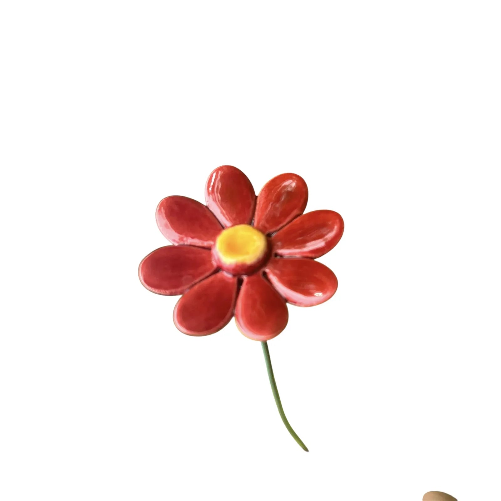 Handmade red ceramic daisy with a glossy finish on a stem, with a vibrant yellow center and glossy crackle glazed finish.