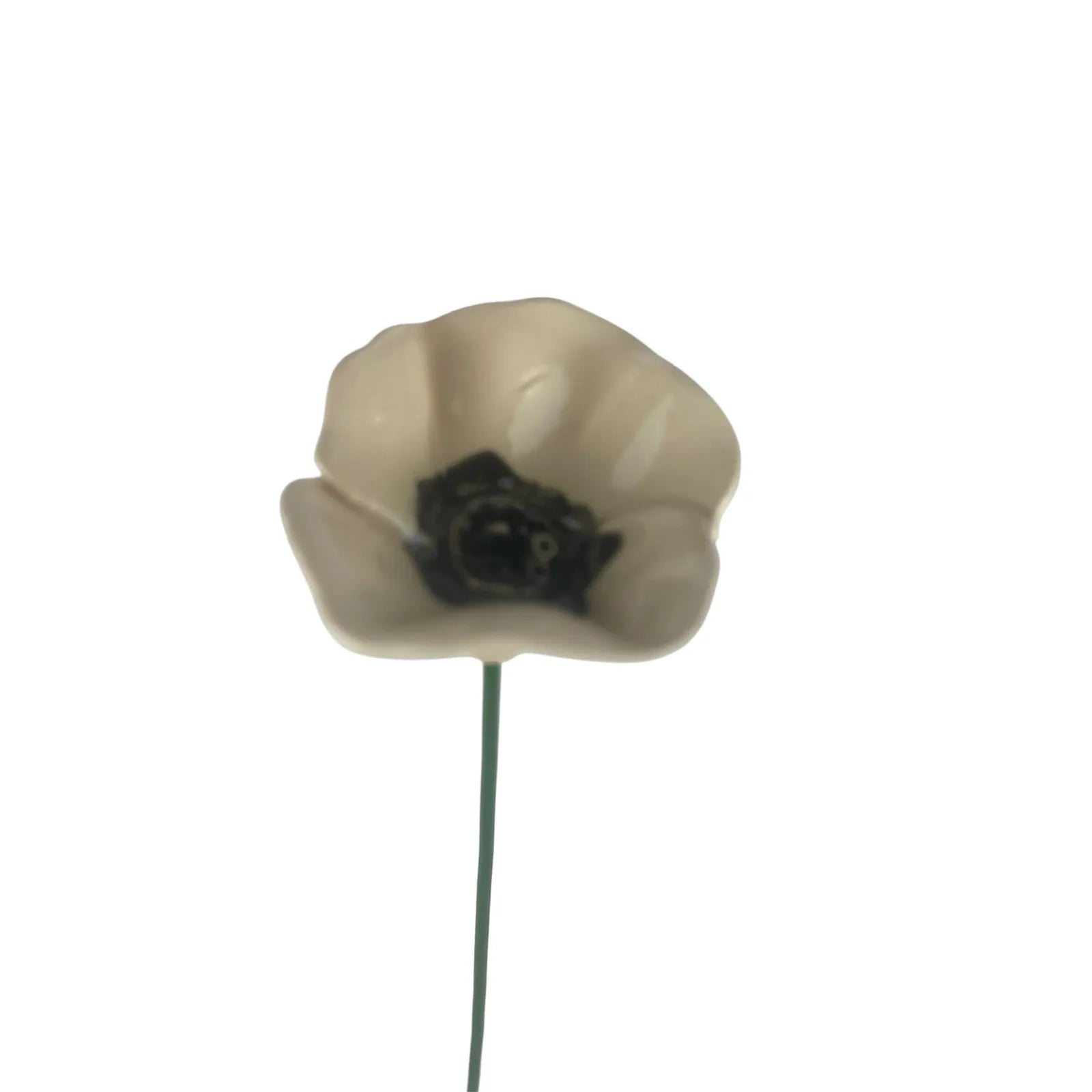 A small handmade white ceramic poppy with a black centre and a crackle glaze finish on a green stem.
