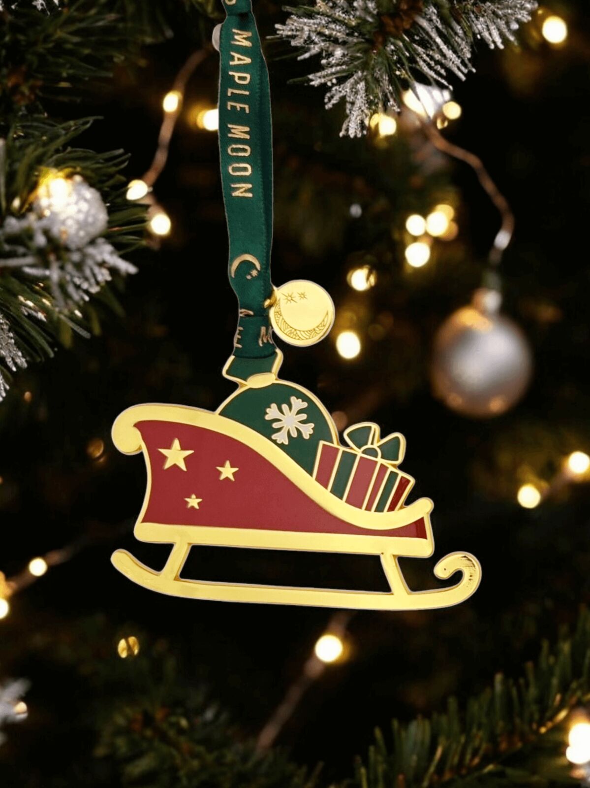 Christmas ornament of a sleigh with presents on a tree with lights