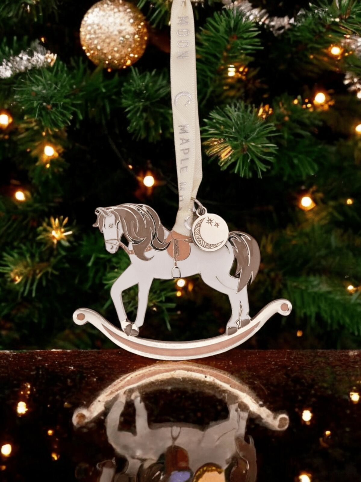 Decorative rocking horse ornament on a Christmas tree with lights and tinsel.