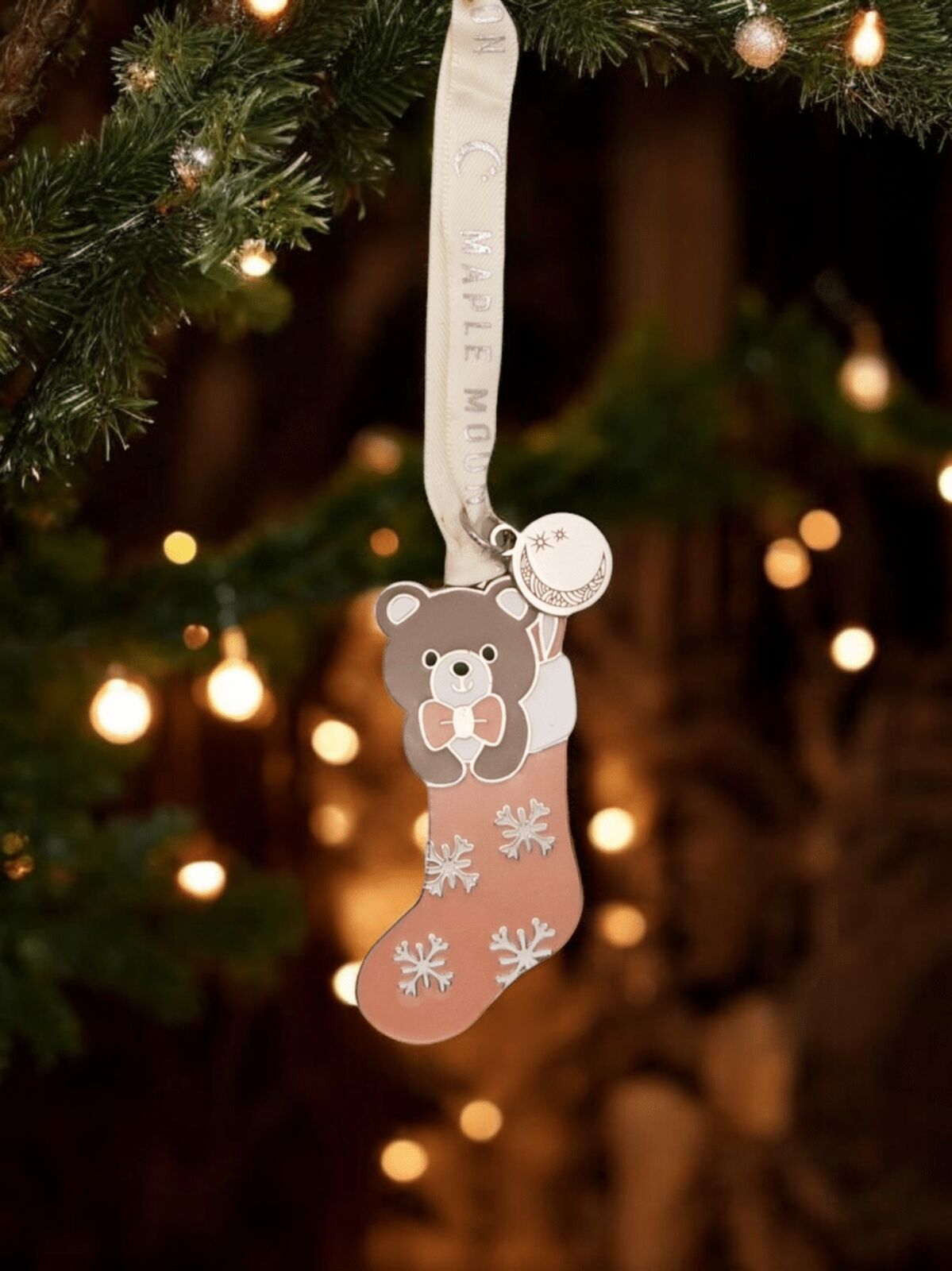 Decorative stocking ornament with a bear design hanging on a Christmas tree.