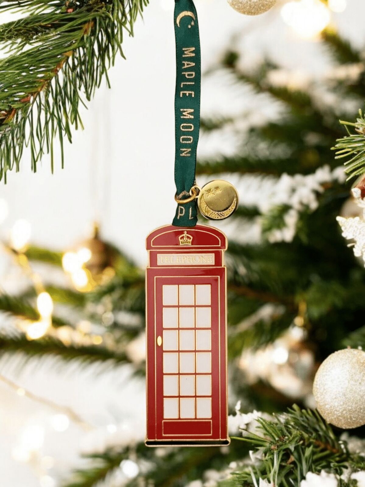 Red telephone box ornament with gold accents on a Christmas tree.