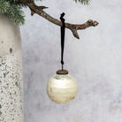 Decorative ornament hanging from a branch against a neutral background