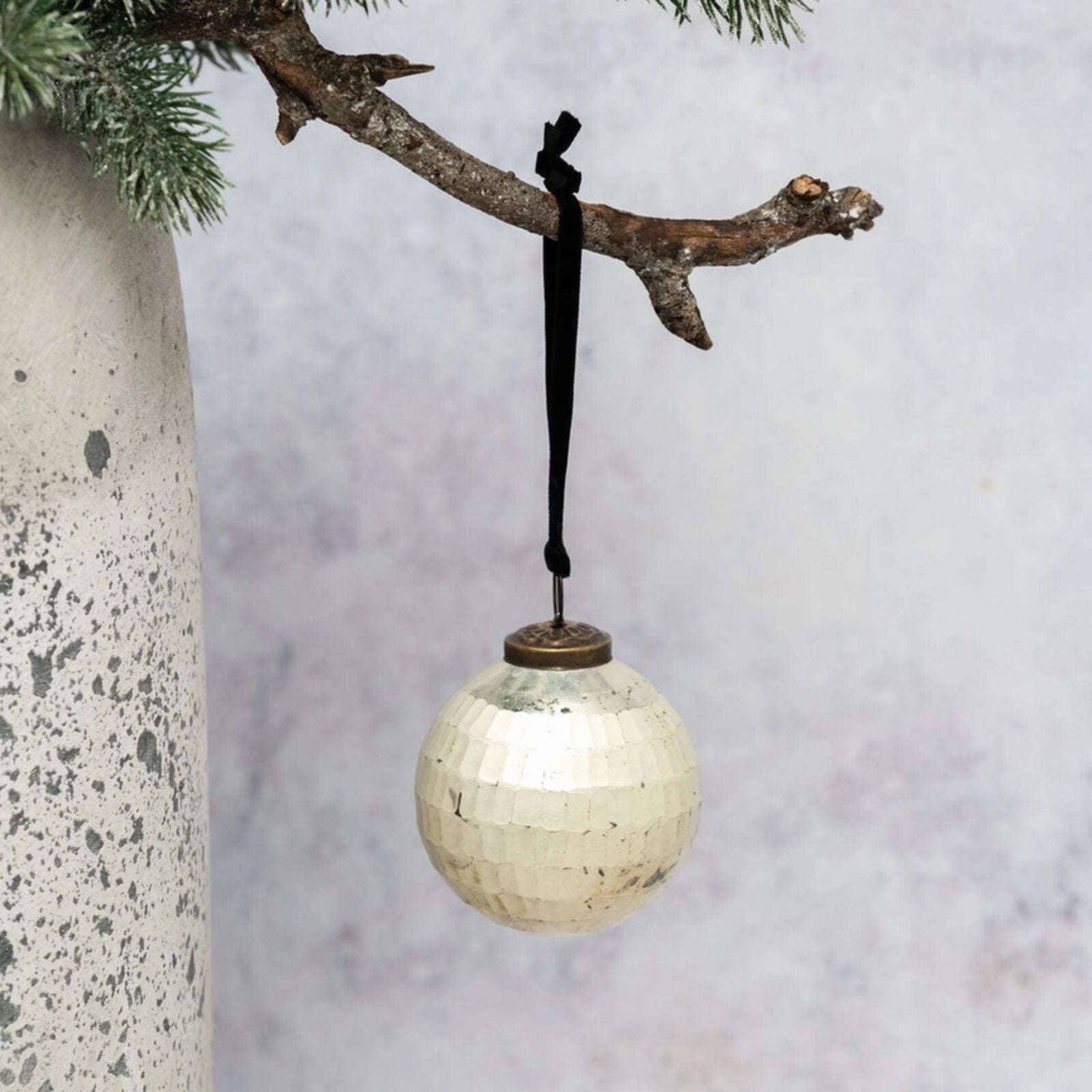 Decorative ornament hanging from a branch against a neutral background