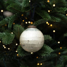 Decorative disco ball ornament on a Christmas tree with lights in the background