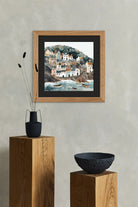 Framed artwork of a coastal scene on a wall with decorative elements below.
