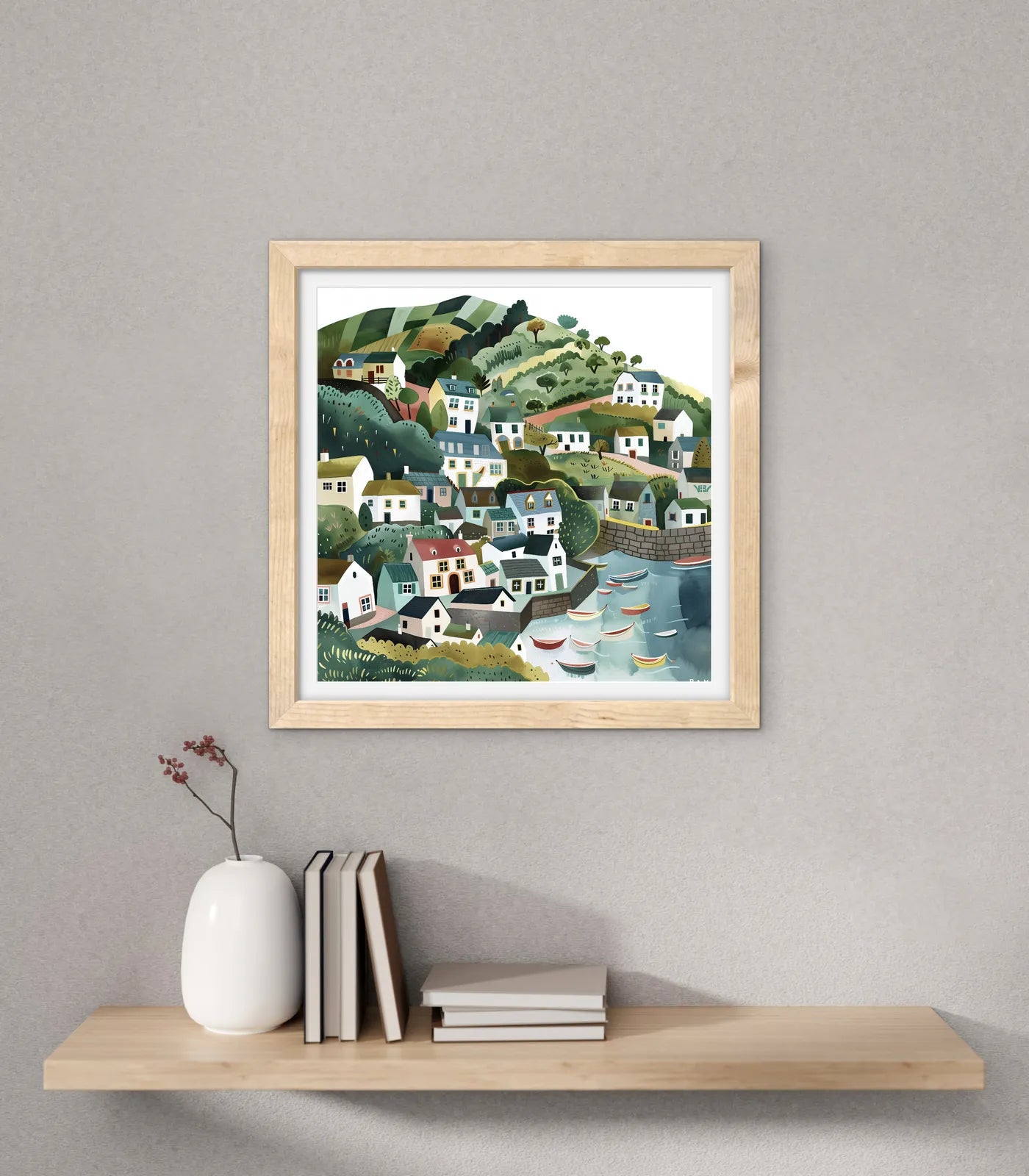 Framed artwork of a coastal village scene on a wall above a shelf with decor items.