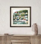 Framed artwork of a coastal village scene on a wall above a wooden cabinet.